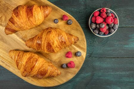 Crunchy French croissants with fresh raspberries and blueberriesの写真素材