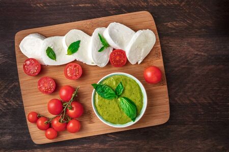 Buffalo mozzarella, cherry tomatoes, basil leaves, and pestoの写真素材