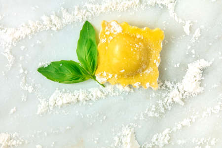 Overhead photo of ravioli with flour and basil leavesの写真素材