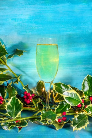 Christmas background with holly leaves and sparkling wineの写真素材