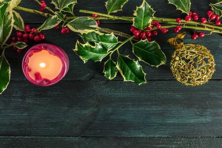 Christmas template with holly branches, candle, and copy spaceの写真素材