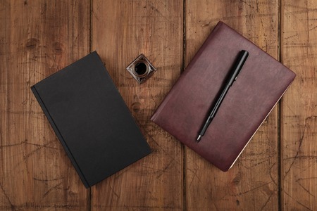 A black book, a leather journal, and ink well and penの写真素材