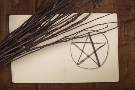 An overhead photo of an open grimoire with a handmade broom and copy spaceの写真素材