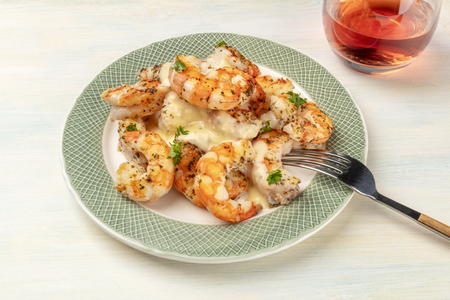 A photo of plate of cooked shrimps on a light background, with a glass of rose wineの写真素材
