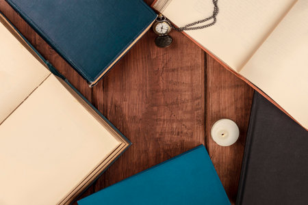 Overhead photo of books on dark background with vintage watch, candle, and copy spaceの写真素材