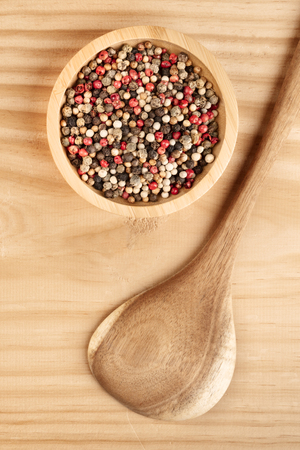 An overhead photo of a mix of various peppers with a wooden spatulaの写真素材