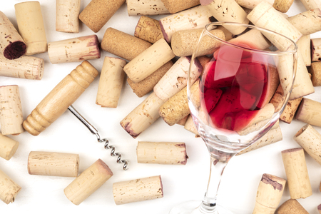 Glass of red wine with corks and corkscrew on a white backgroundの写真素材