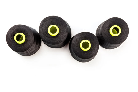An overhead photo of large black thread spools, shot from above on a white background with copy...