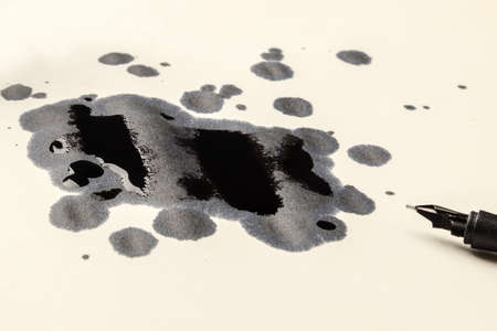 A photo of drops of ink and a nib pen, with copy spaceの写真素材