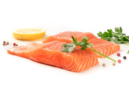 Slices of salmon with lemon, parsley, and pepper, on a white background with copy space