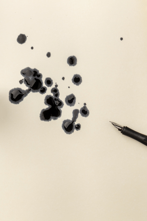 An overhead closeup photo of drops of ink and a nib pen, with copy spaceの写真素材