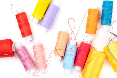 Overhead photo of thread spools of various colors on white with copy space