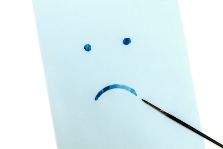 Blue, sad face hand painted on blue paper in watercolor, depression concept, with copy spaceの写真素材