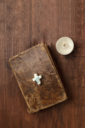 Old bible with a cross and a candle on a dark background with copy spaceの写真素材
