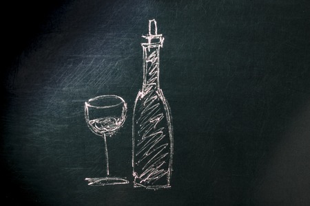 A photo of a simple drawing of a glass and a bottle of wine, made with chalk on a blackboard, with copy spaceの写真素材