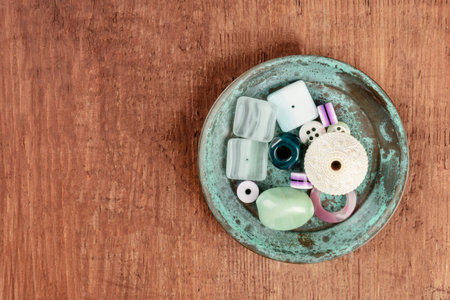 An overhead photo of various beads in a small teal blue plate, with copy space