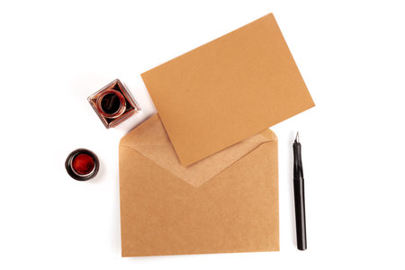 An overhead photo of an ink well with a brown craft card in an envelope, with an ink pen and copy...