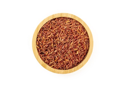 Red rice, shot from the top in a wooden bowl on a white background with a place for textの写真素材