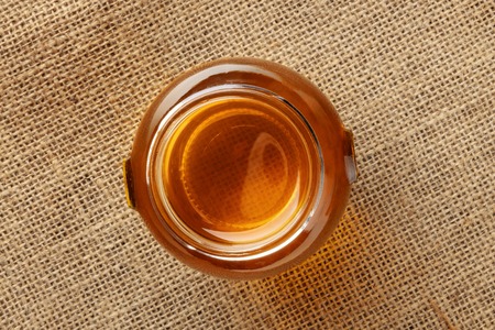 A photo of jar of honey, shot from the top on a rustic burlap background with copy spaceの写真素材