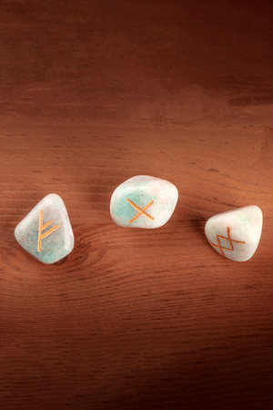 A closeup overhead photo of Norse runes from the Futhark alphabet, stones with symbols used in...