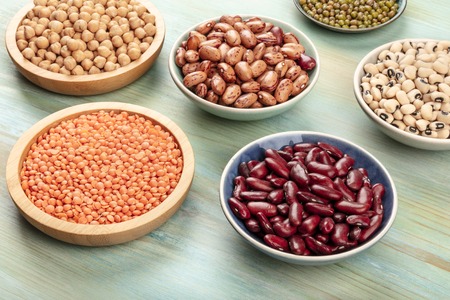 Various types of legumes on a teal background. Red kidney beans, lentil, chickpea, soybeans, black-eyed peasの写真素材