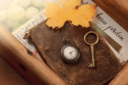 Nostalgia. A vintage pocket watch, a key, autumn leaves and old letters and cards in a wooden drawerの写真素材