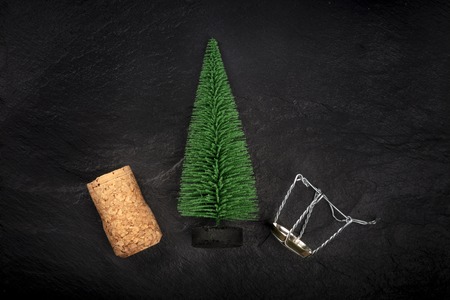 A photo of a little Christmas tree with a champagne cork and closure, shot from the top on a black background with a place for textの写真素材