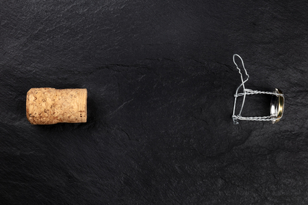 A photo of a champagne cork and closure, shot from the top on a black background with a place for textの写真素材