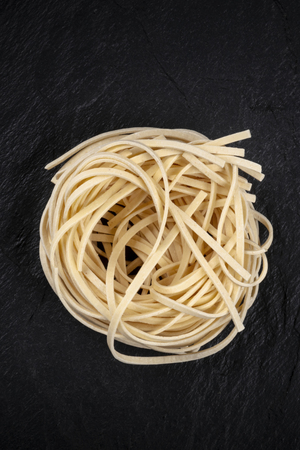 A photo of udon noodles in the shape of a nest, shot from above on a dark background with copy spaceの写真素材