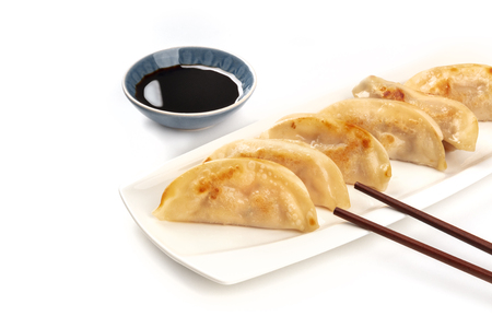 Gyozas, Asian dumplings, on a white background with chopsticks, soy sauce and copy spaceの写真素材
