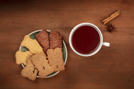An overhead photo of an assortment of traditional Christmas Spekulatius cookies, shot from the top on a dark rustic background with hot chocolate, spices, and a place for textの写真素材