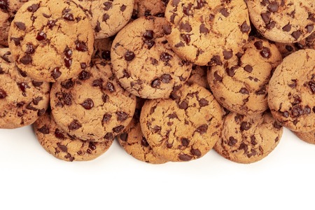 Many freshly baked chocolate chip cookies, shot from the top on white, an abstract sweet biscuits background with copy spaceの写真素材