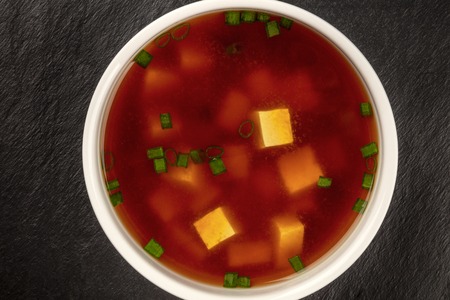 A closeup of miso shiru soup with tofu and scallions, shot from the top on a black backgroundの写真素材