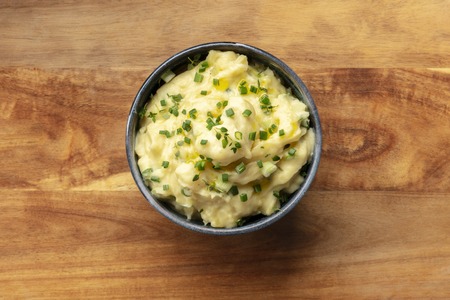 Pomme puree, an overhead photo of a bowl of mashed potatoes with herbs, shot from the top on a rustic background with a place for textの写真素材