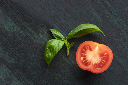 A closeup photo of a fresh organic tomato with basil leaves and a place for textの写真素材