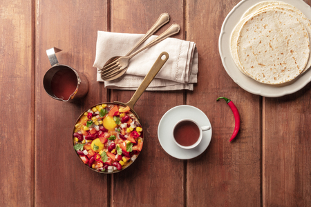 Mexican brekfast. Huevos rancheros, the fried eggs, shot from the top with the pico de gallo salad, hot chocolate, and tortillas on a dark rustic wooden backgroundの写真素材