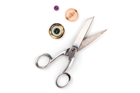 An overhead photo of vintage scissors with buttons, shot from the top on a white background with a...