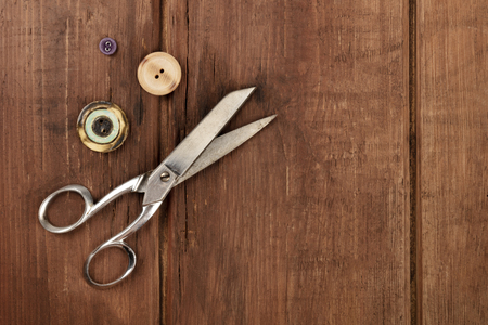 Vintage scissors and buttons, shot from the top on a dark rustic wooden background with a place for textの写真素材