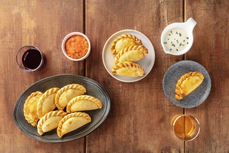 Empanadas with sauces and wine, shot from the top on a dark rustic wooden background with a place for textの写真素材