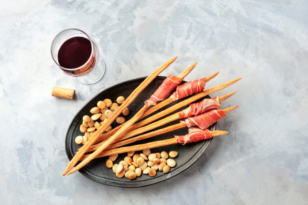 Italian grissini with wine and parma ham, with roasted almonds, top view