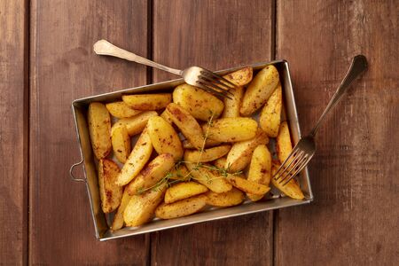 Potato wedges, oven baked with thyme, top shot on a baking sheetの写真素材