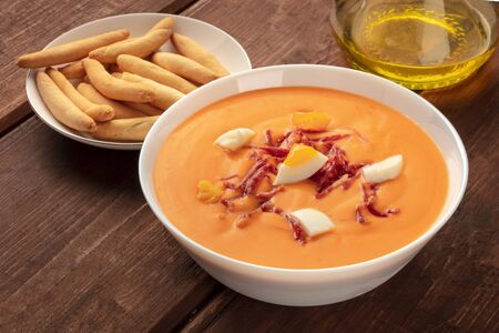 Salmorejo, Spanish cold tomato soup, on a rustic wooden background with picos and olive oilの写真素材