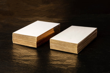 White business cards with golden edges mockup on a black background