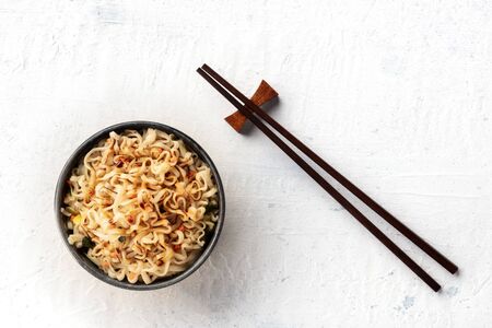 Instant soba noodles with scalliions, carrot, and a dark sauce, shot from the top with chopsticks and copy spaceの写真素材