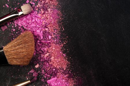 Make-up brushes and crushed cosmetics, shot from above on a black background with a place for text, a beauty design template for a makeup bannerの写真素材