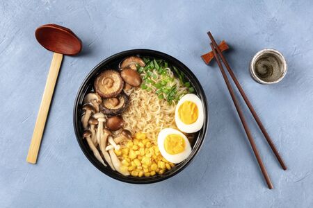 Ramen. Soba with eggs, mushrooms, and vegetables, shot from the top with sake, traditional wooden spoon, and chopsticksの写真素材