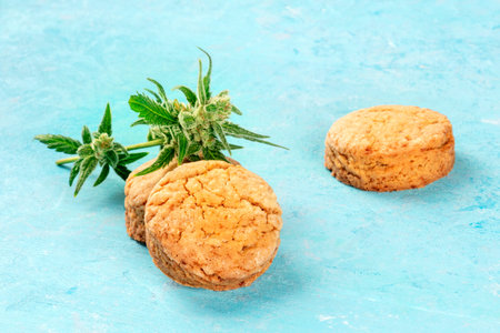 Cannabis butter cookies with marijuana buds close-up, homemade healthy biscuits on a blue backgroundの写真素材