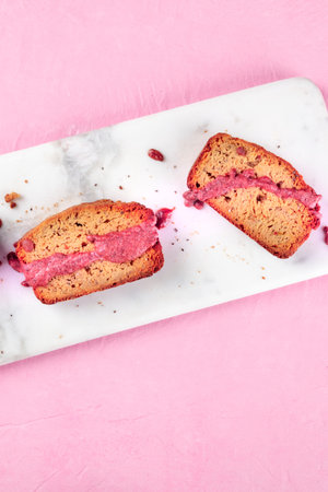 A close-up of a seed cake with ruby chocolate, shot from the top on a pink background with a place...