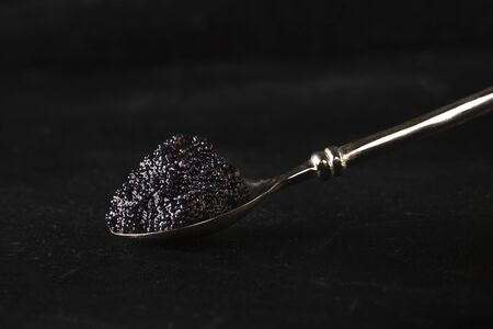 Black caviar on a spoon close-up on a dark background with a place for textの写真素材