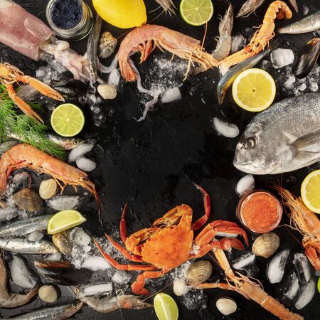 Fish and seafood variety, a square flatlay top shot, a frame with copy space on a dark background. Sea bream, shrimps and prawns, crab, sardines, squid, mussels and other fresh products on iceの写真素材